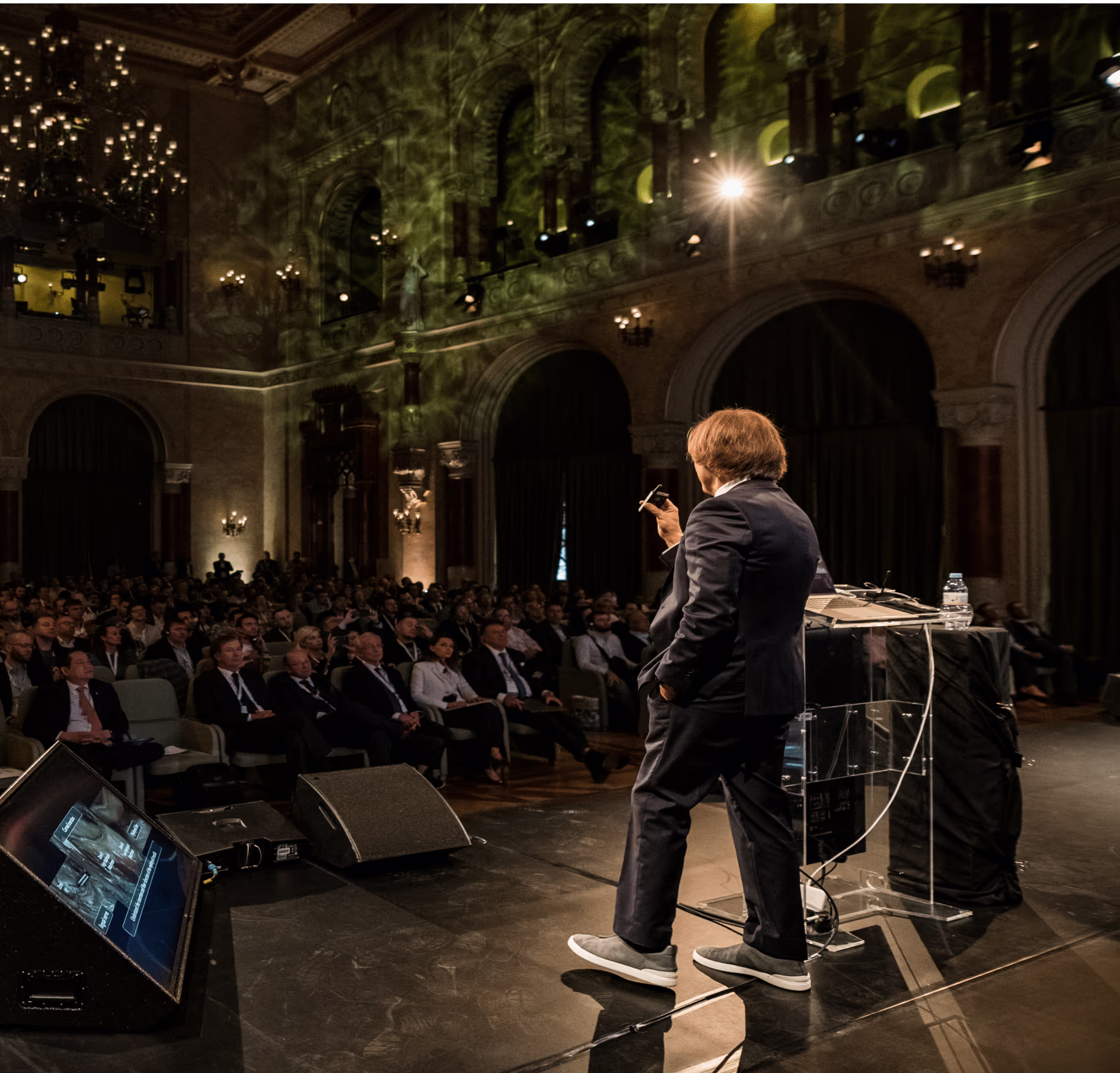 Dr. Urban lecturing to a seated audience in a grand hall