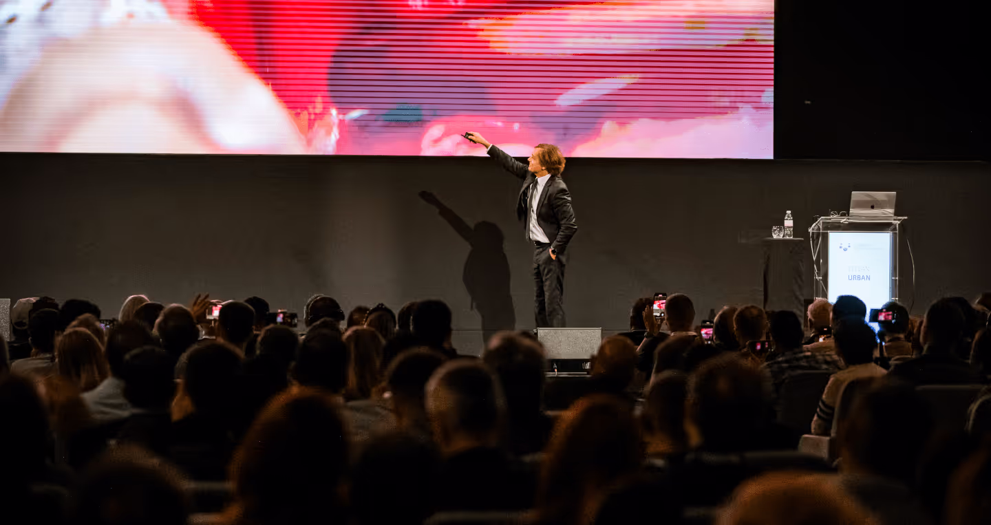 Dr. Istvan Urban presenting on stage to a full auditorium